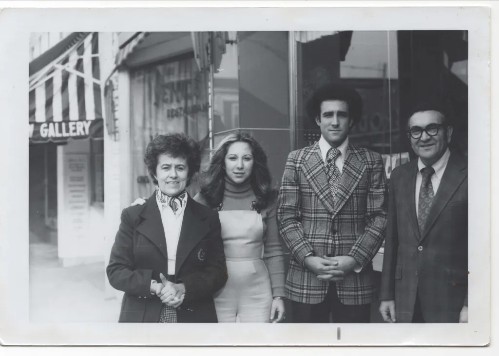 Four people, two men and two women, pose outside a gallery in a black and white photo.