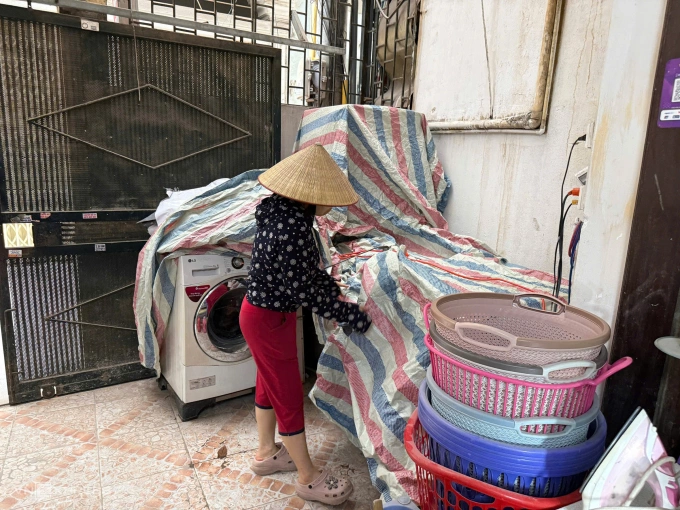 Ms. Phuong used a tarpaulin to cover 6 washing machines and dryers placed in front of her family's yard at her home in alley 12 Chinh Kinh street, Thanh Xuan ward, on the morning of May 19. Photo: Quynh Nguyen