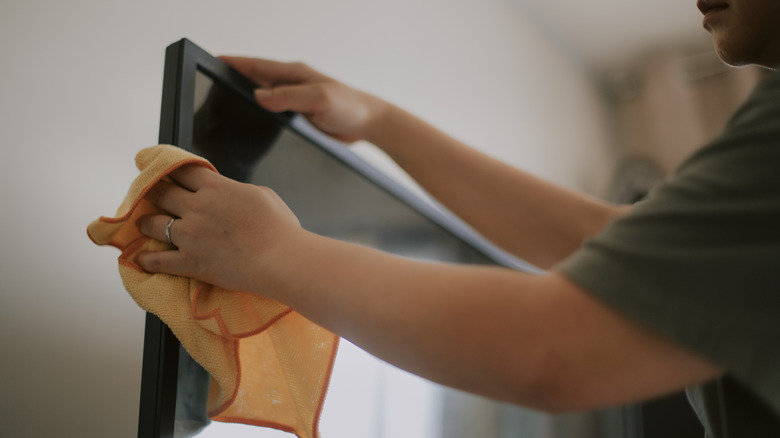 Person using a microfiber cloth to clean a large display.