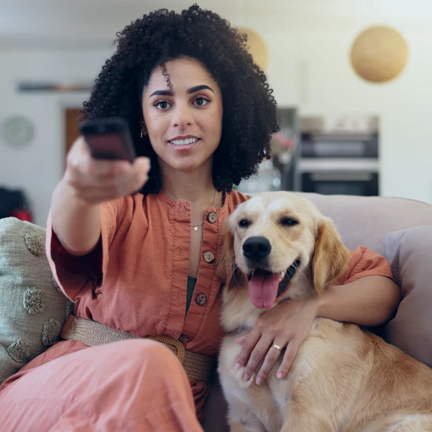 woman watching horror movie with dog on couch 
