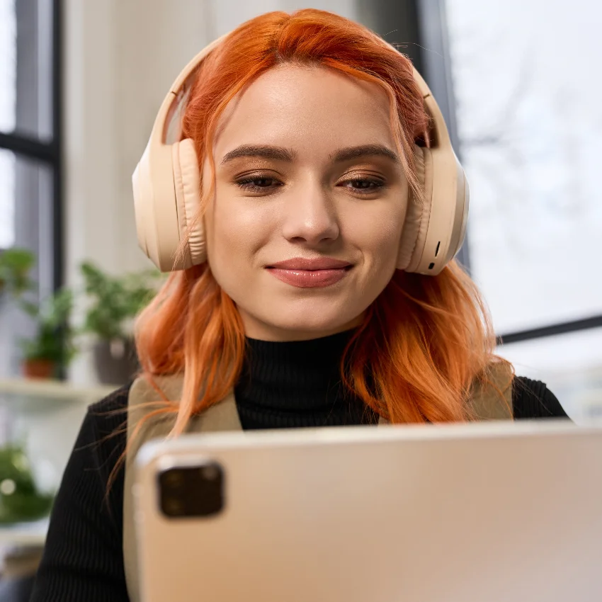 gen z woman working on laptop wearing headphones