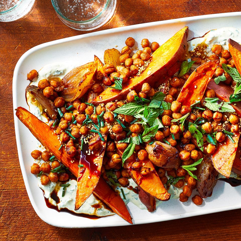 a recipe photo of the Sheet-Pan Spiced Chickpeas & Sweet Potatoes with Herby Yogurt served on a platter Credit: Photographer: Brie Goldman Food Stylist: Lauren McAnelly Prop Stylist: Holly Raibikis