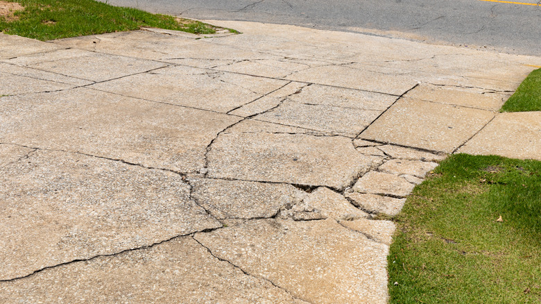 A cracked and broken aggregate concrete driveway