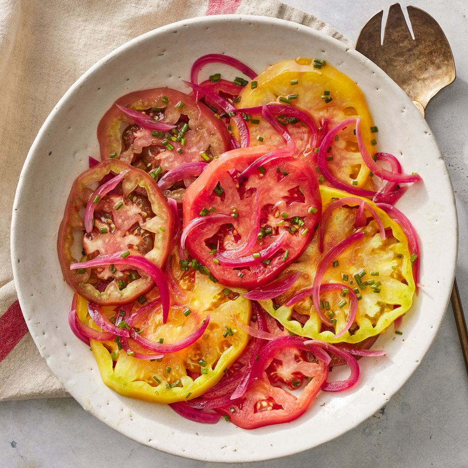 Overhead view of a rustic off-white plate of Heirloom Tomato Salad with Pickled Onions recipe Credit: Photographer: Fred Hardy, Food Stylist: Jennifer Wendorf