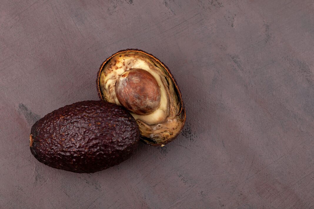 Rotten, spoiled avocado on brown background. Rotten, spoiled avocado on brown background.