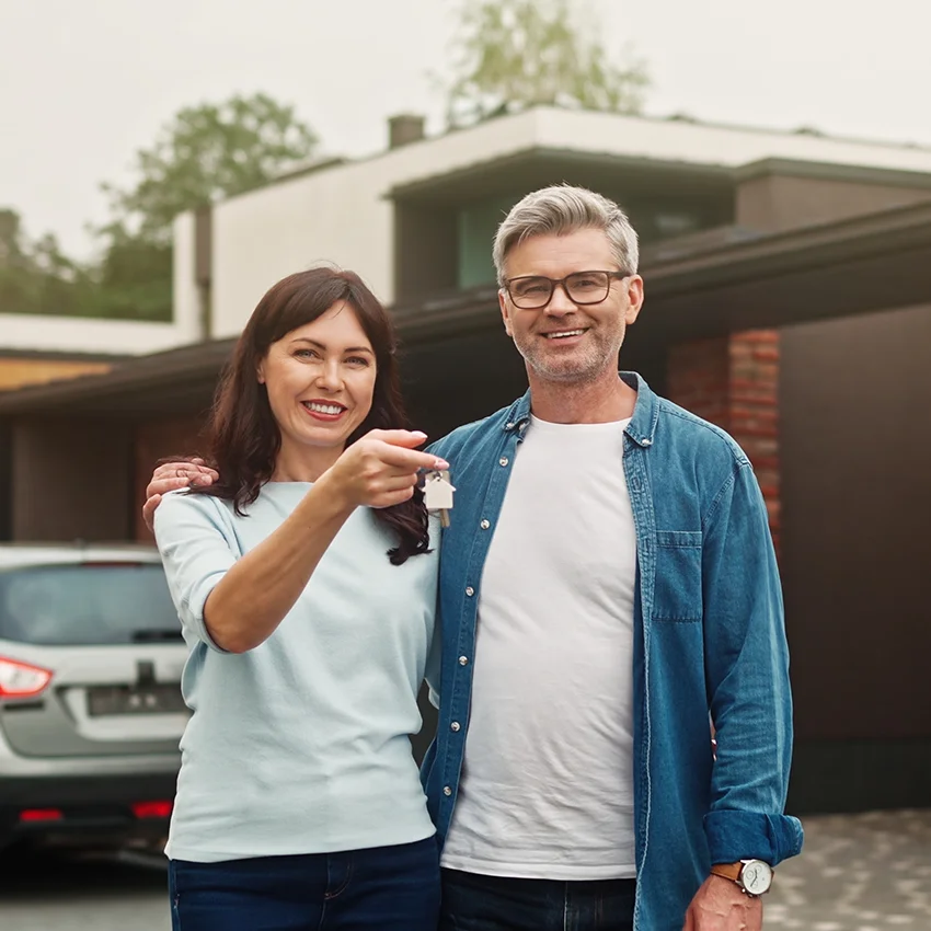gen x couple holding up keys after buying house