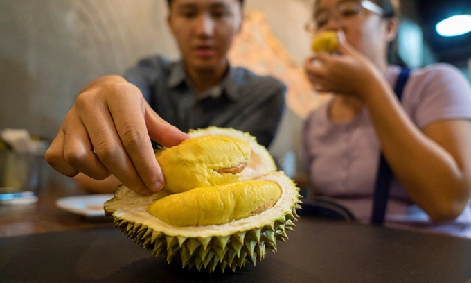 A customer reaches for a durian pulp at a coffee shop in Singapore. Photo by AFP
