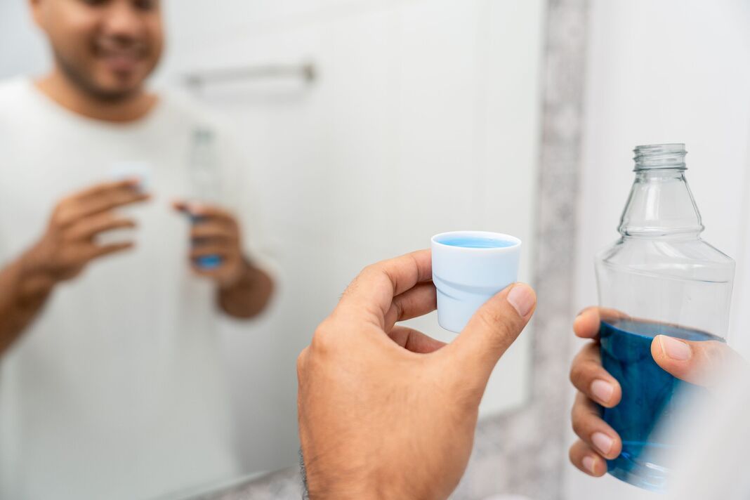 Young man is gargling with a blue mouthwash. For good dental health and fresh bad breath. Take care and good dental health fresh breath with mouthwash Young man is gargling with a blue mouthwash. For good dental health and fresh bad breath. Take care and good dental health fresh breath with mouthwash