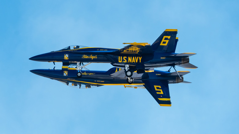 Two U.S. Navy Blue Angels F/A‑18 jets fly in a tight mirror formation, one inverted above the other.