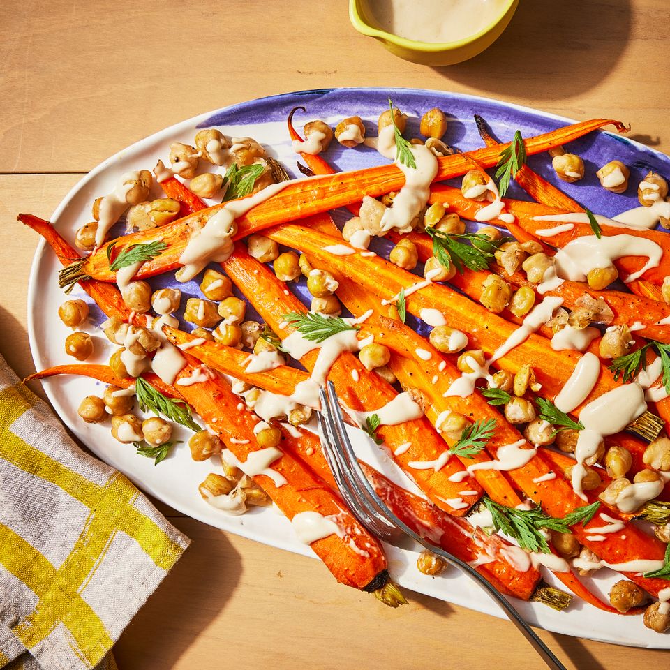 A serving plate with roasted sliced carrots, topped with a tahini sauce and crispy chickpeas Credit: Photographer: Jen Causey, Food Stylist: Melissa Gray, Prop Stylist: Shell Royster