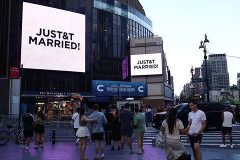 Getty Images People watch giant screens showing the message "JUST&T MARRIED!" (T&T for Taylor and Travis) outside Madison Square Garden, the reported venue for the wedding celebrations of pop singer Taylor Swift and pro-athlete Travis Kelce.