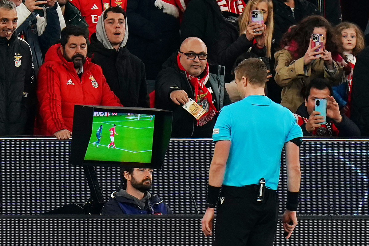 LISBON, PORTUGAL - FEBRUARY 18: A fan of SL Benfica offers Match Referee, Glenn Nyberg a fifty euro note as he checks the VAR screen during the UEFA Champions League 2024/25 League Knockout Play-off second leg match between SL Benfica and AS Monaco at Estadio da Luz on February 18, 2025 in Lisbon, Portugal. (Photo by Gualter Fatia / Getty Images)
