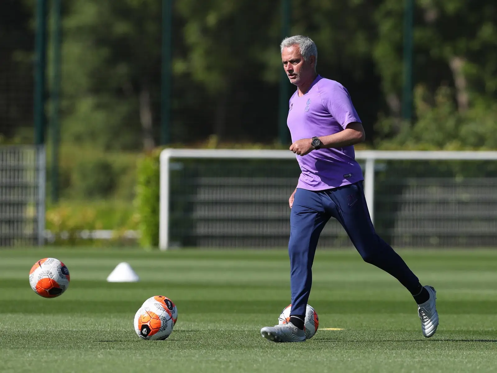 Jose Mourinho training on a football pitch with soccer balls.