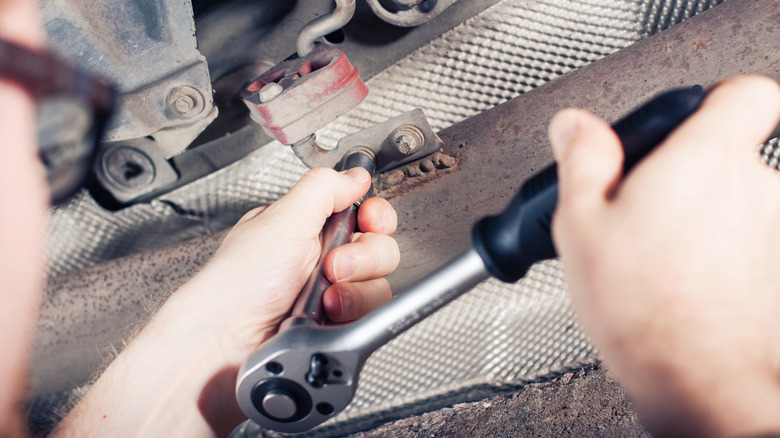 Person loosening bolt in a car engine