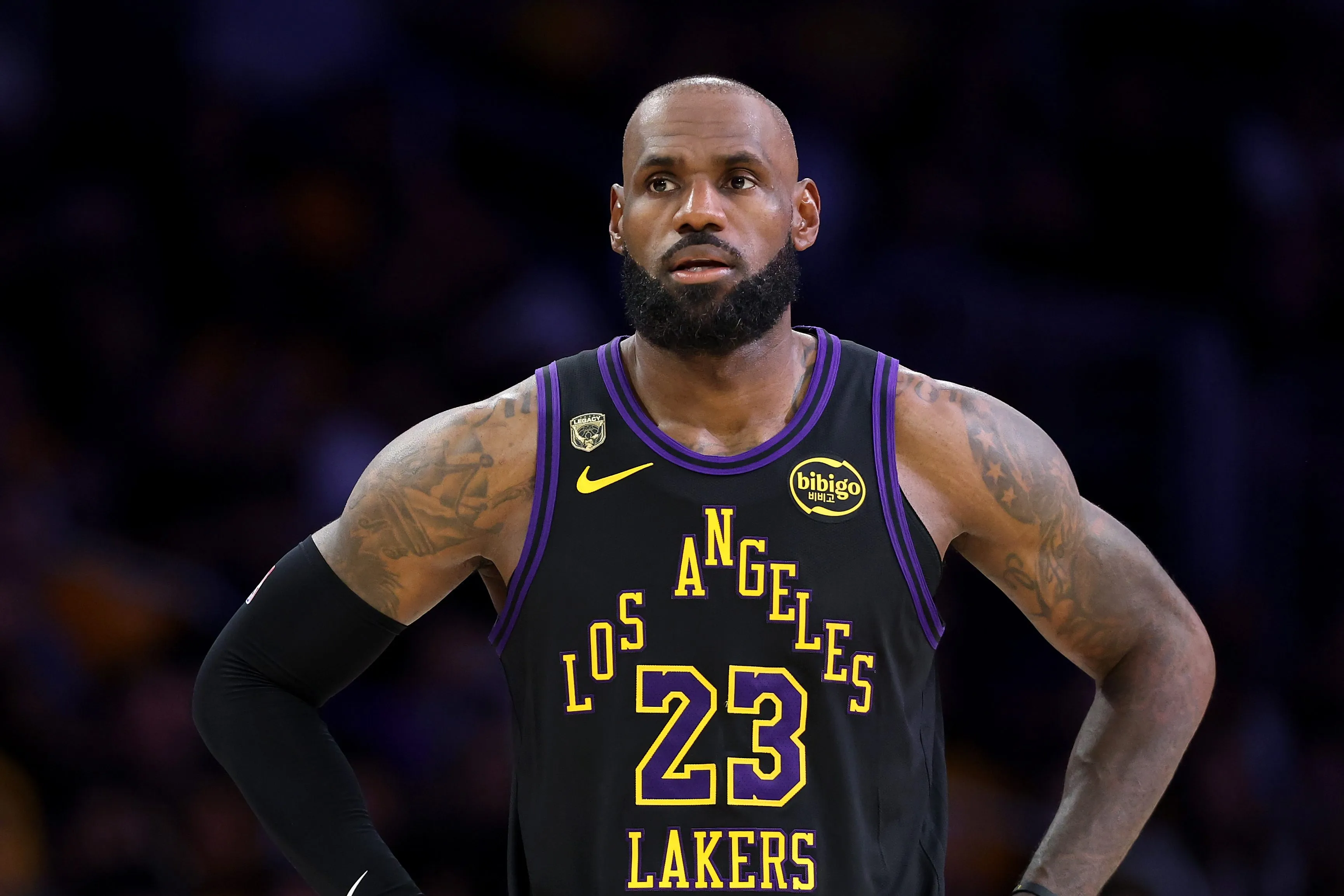 LeBron James in a black Los Angeles Lakers jersey with yellow and purple trim, number 23, with hands on his hips.
