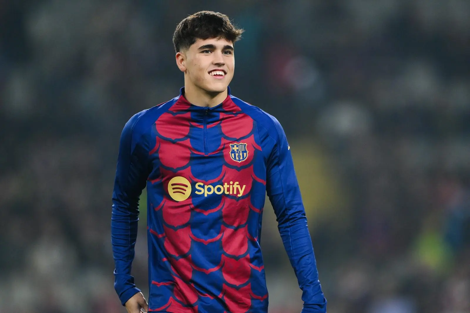 Young player in Barcelona jersey with Spotify logo smiling on the field.