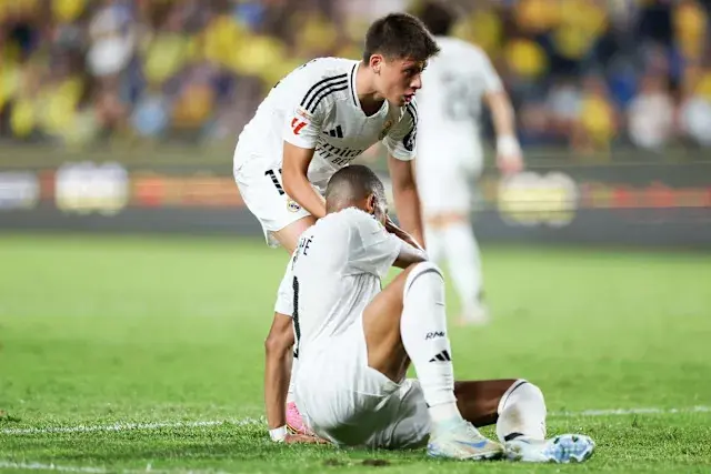 Arda Guler helping Kylian Mbappe on the field during a match.