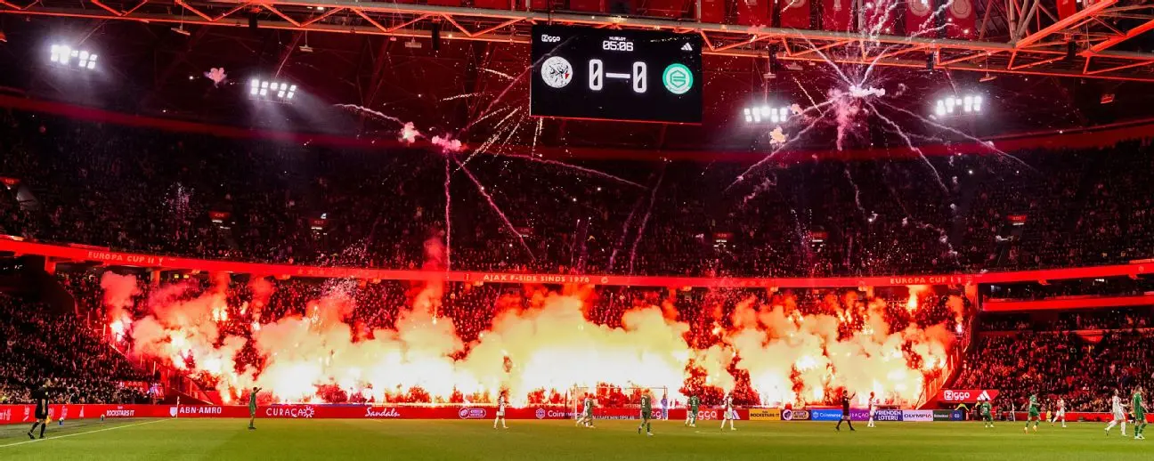 Fans lighting red flares in the stands at the Johan Cruyff Arena during an Ajax Amsterdam match