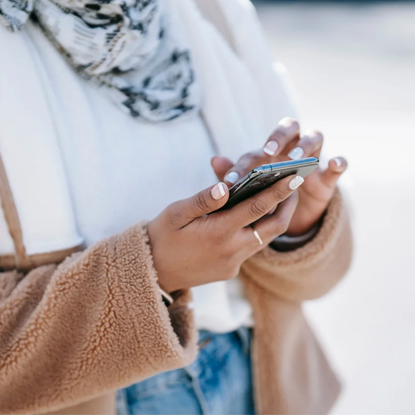 Person holding and scrolling on a smartphone with their thumb while experiencing discomfort in their hand and wrist