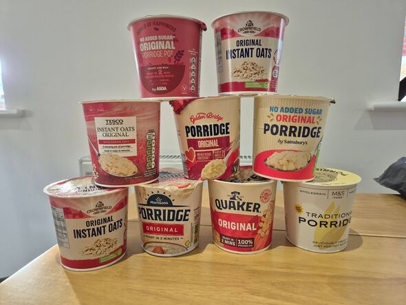 A collection of assorted frozen food containers neatly stacked on a wooden table against a white backdrop. Each container varies