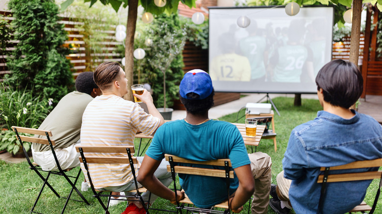A group of friends watching sports outdoors on a projector during the day