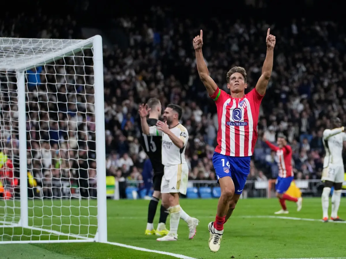 Marcos Llorente in an Atletico Madrid kit celebrating a goal with arms raised in a stadium