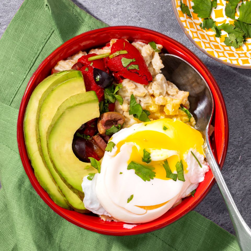 Savory oatmeal bowl topped with avocado slices roasted vegetables a poached egg and herbs placed on a green napkin Credit: Abbey Littlejohn
