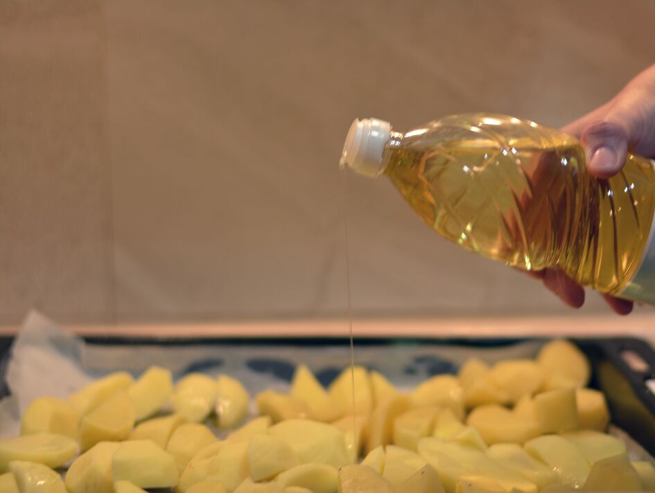 Woman adding oil to potatoes Woman adding oil to potatoes