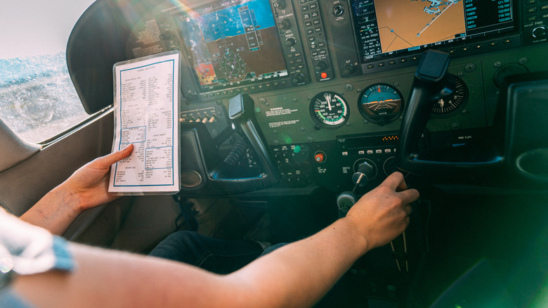 A pilot on a small aircraft going through a printed checklist pre-flight