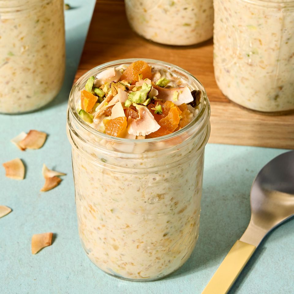Jar of overnight oats topped with nuts and dried fruits spoon nearby multiple jars in the background Credit: Photographer: Jen Causey.