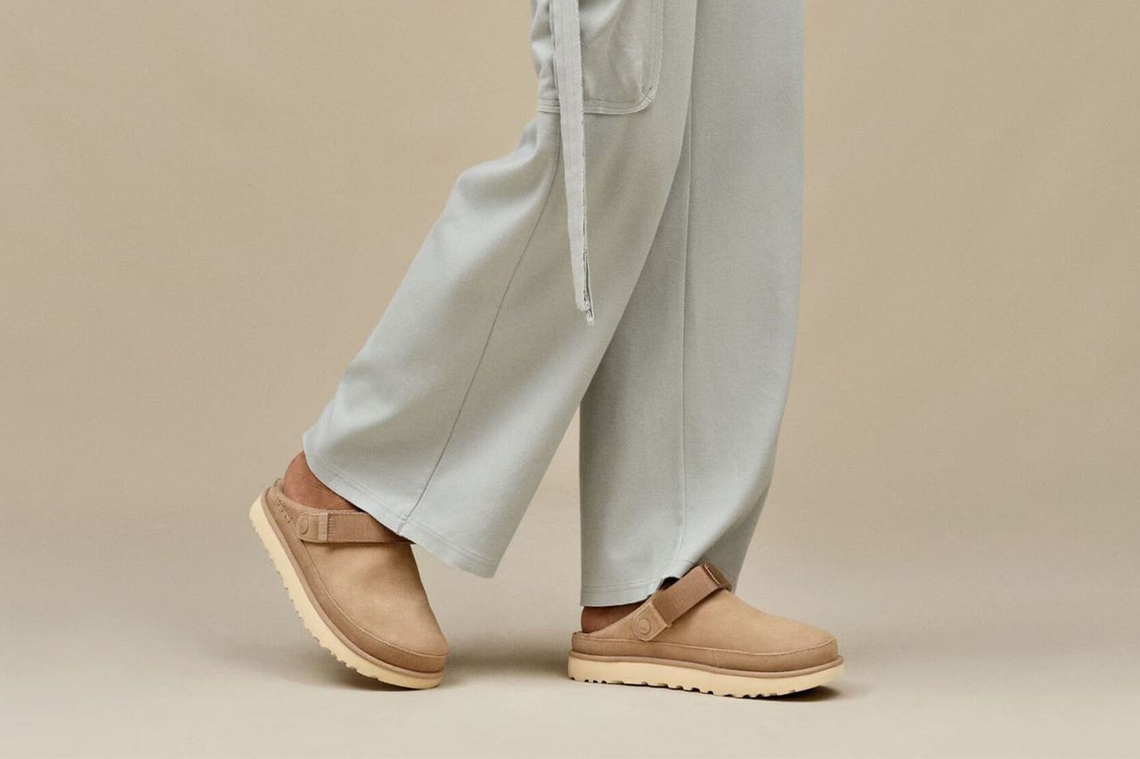 A person wearing lightcolored pants and a pair of beige clogs with a strap walking on a neutral background Credit: Nordstrom Rack