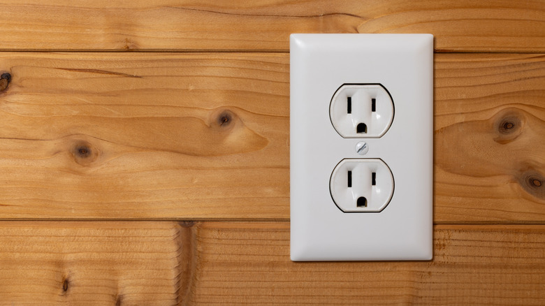 An electrical outlet on a wood panel wall.