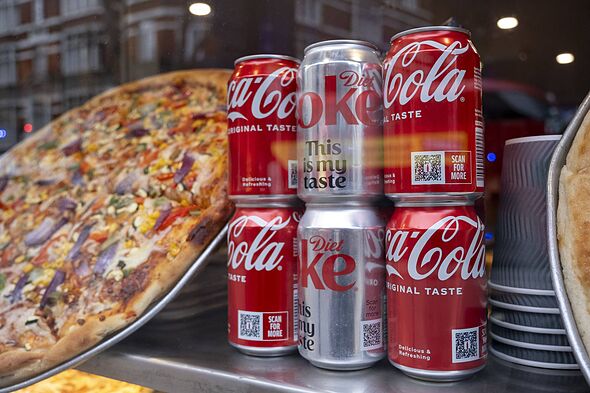 Pizza takeaway in a cafe window alongside cans of Coca Cola and Diet Coke in January 2025 in London Pizza takeaway in a cafe window alongside cans of Coca Cola and Diet Coke in January 2025 in London