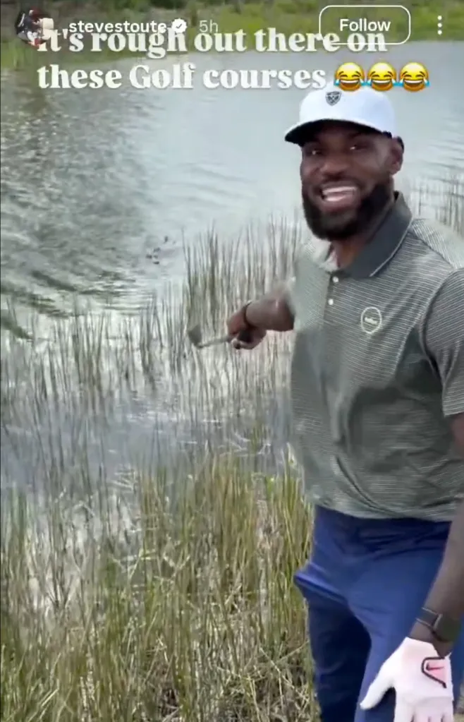 LeBron James smiles while holding a golf club over a water hazard.