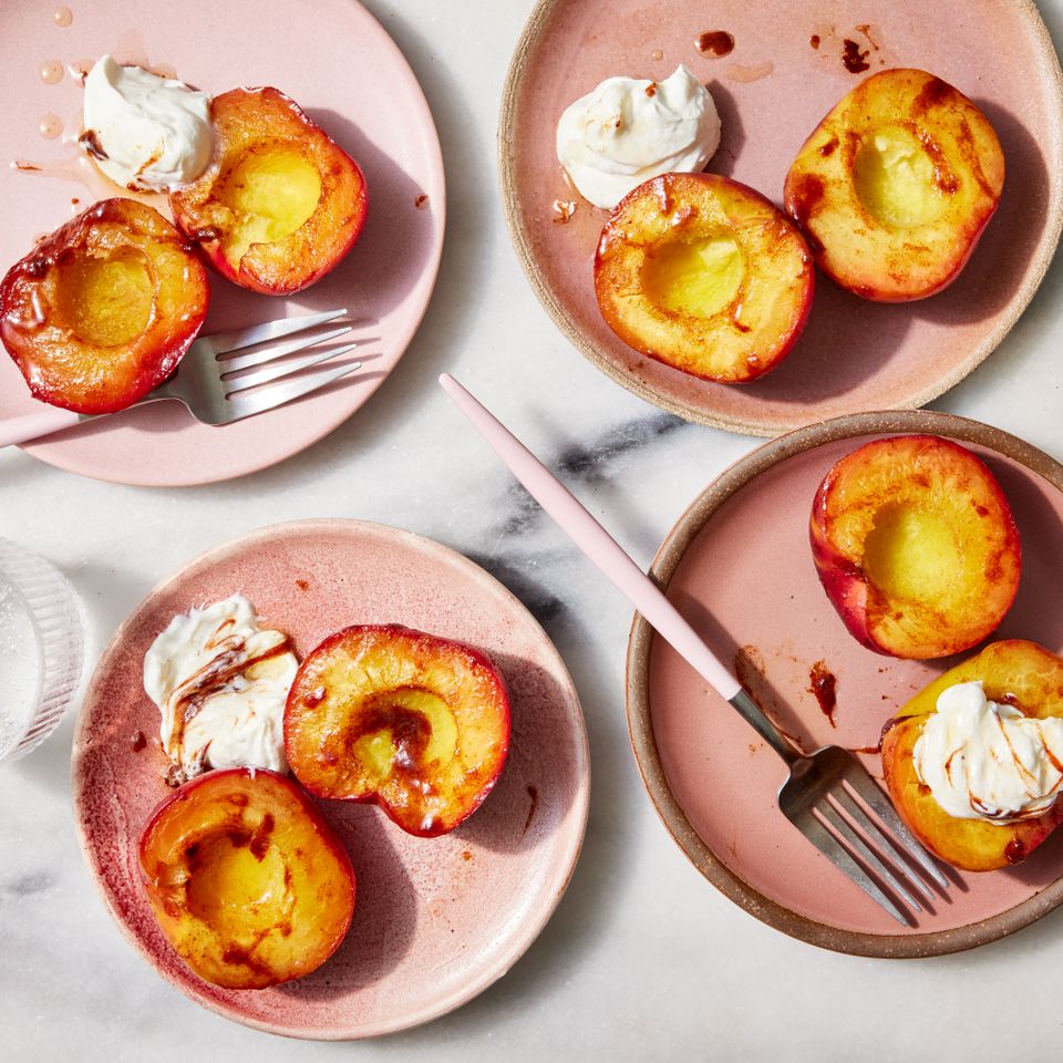 Overhead view of four pink serving plates of Baked Peaches recipe Credit: Photographer: Jen Causey, Food Stylist: Torie Cox, Prop Stylist: Claire Spollen