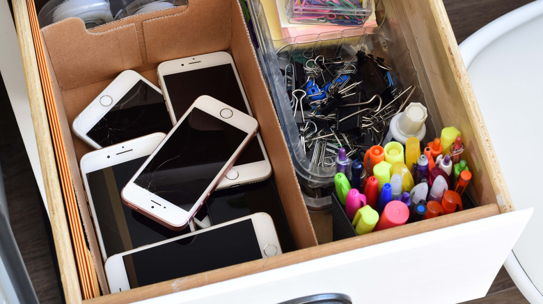 A box of old, broken iPhones in a junk drawer.