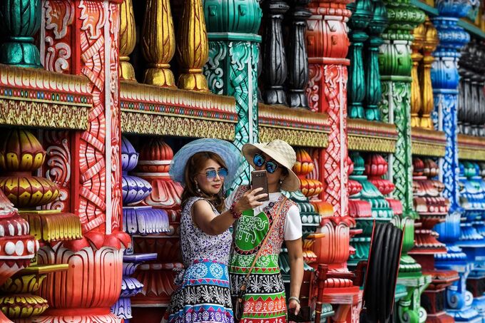 Two tourist take pictures at a temple in Batu Caves, near Kuala Lumpur on August 6, 2019. Photo by AFP