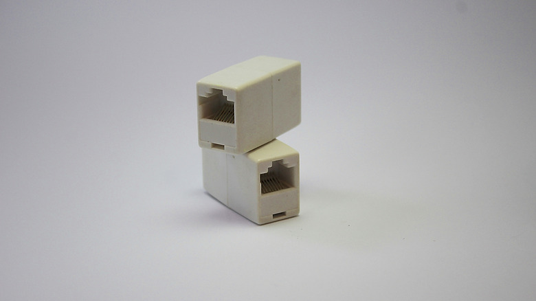 two white ethernet couplers placed on top on one another against a light background