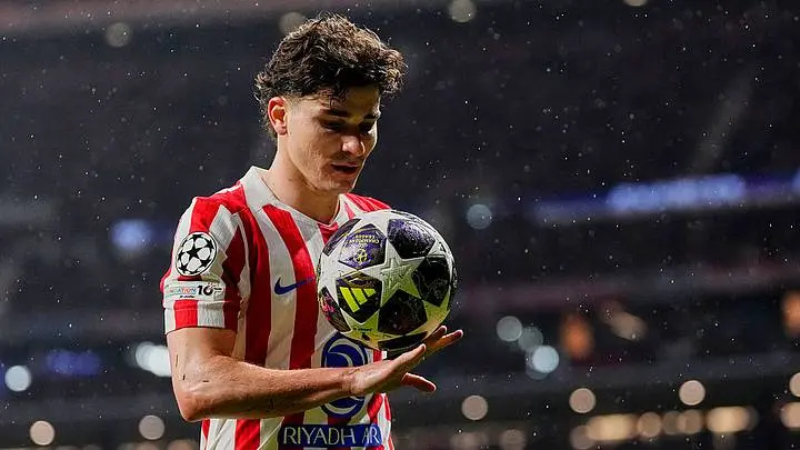 Julian Alvarez wearing an Atletico Madrid jersey holding a Champions League football