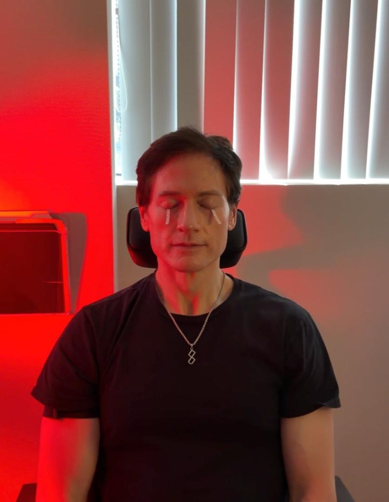 Biohacker Bryan Johnson with his eyes closed and white strips on his eyelids.