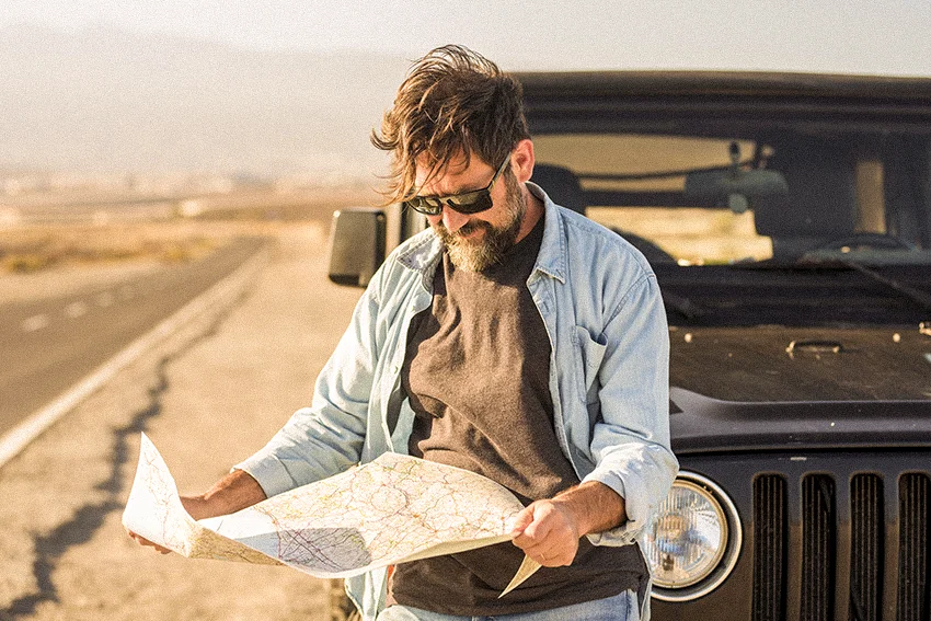 man using a paper map in the 90s