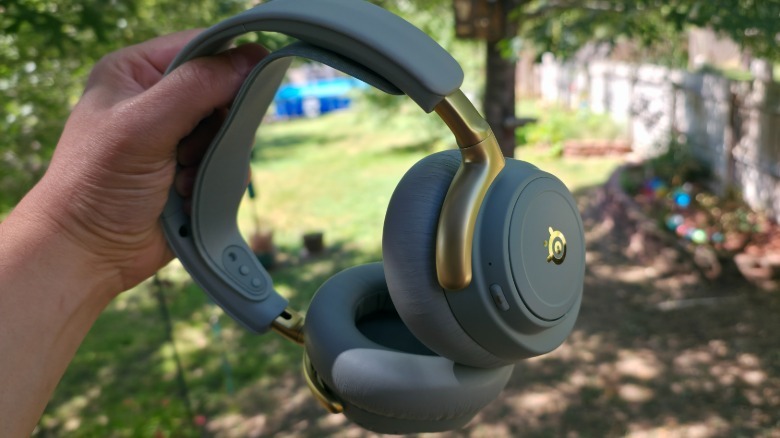 A hand holding the Arctis Nova Elite headset