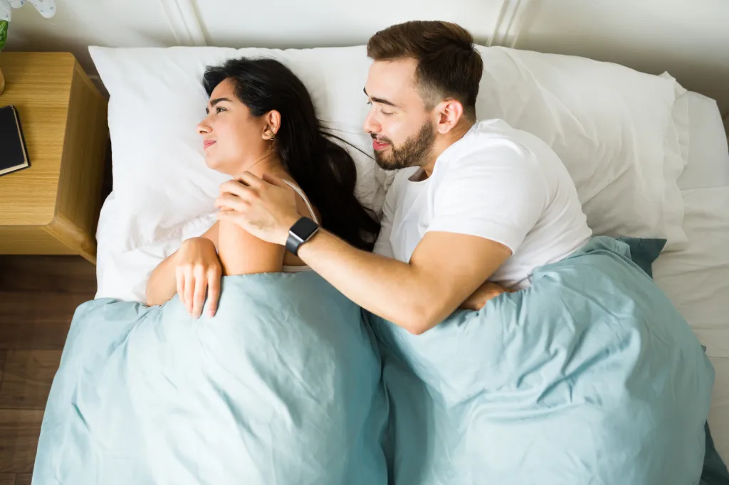Man grabbing woman in bed.