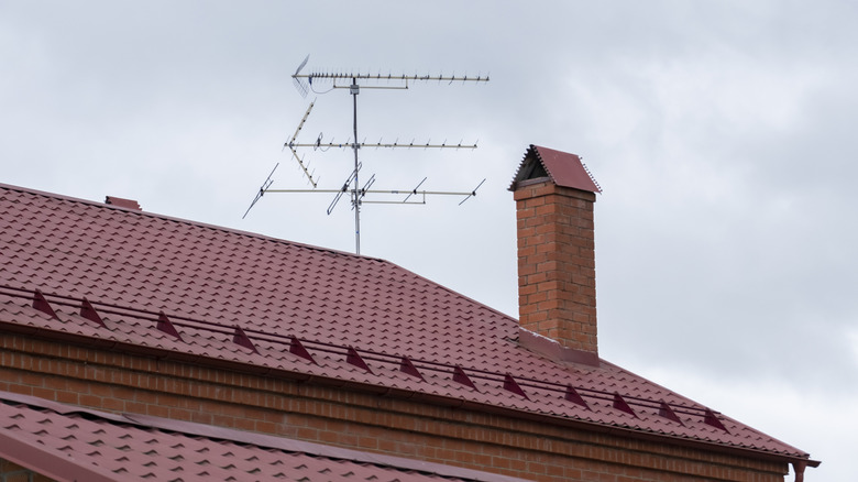 TV antenna mounted on a red roof of a house next to the chimney