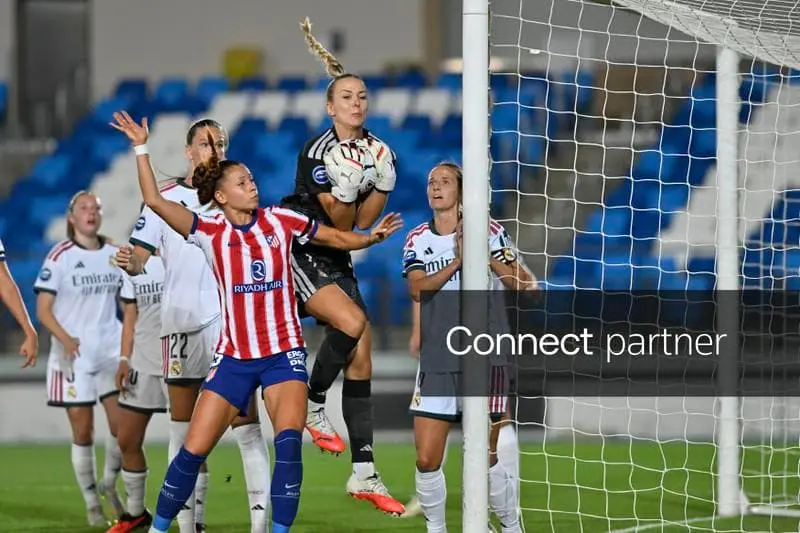Atletico Madrid Femenino player in red and white stripes competing for the ball against Real Madrid players.
