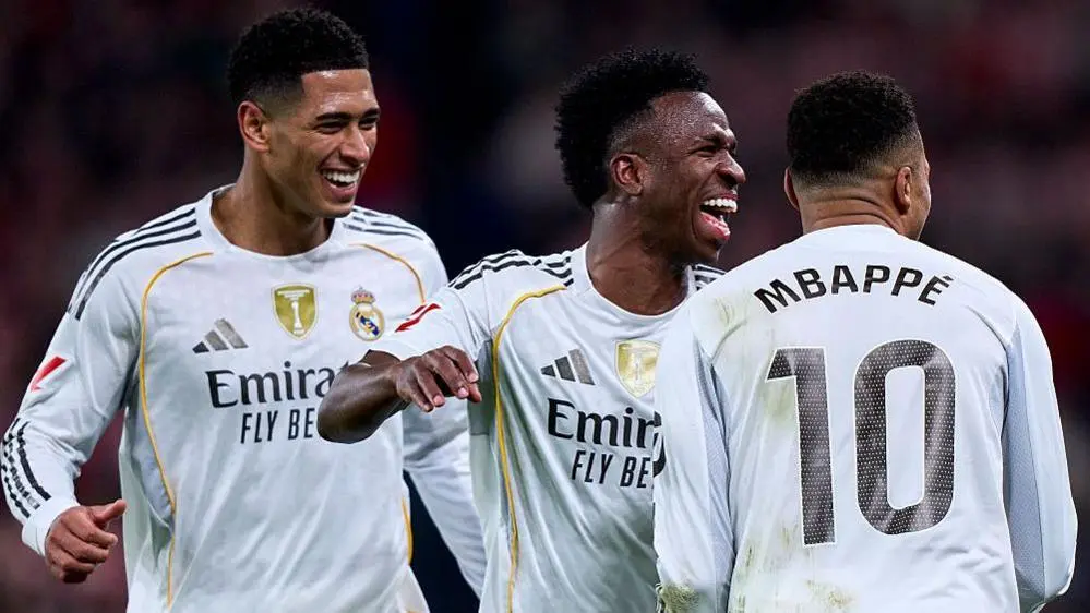 Jude Bellingham, Vinicius Junior, and Kylian Mbappe celebrating together in Real Madrid kits