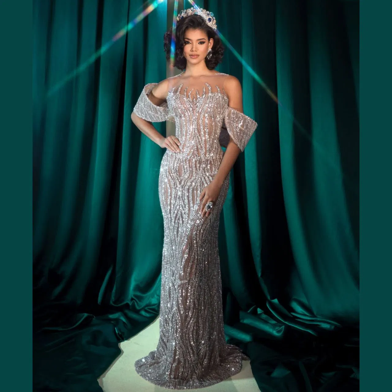 This look of Johari Mol Dominguez has a royal touch. She wore a silver glitter gown, which had an off-shoulder fitted silhouette and intricate sequin work. Drop sleeves give it a dramatic feel, while the crown or tiara on the head enhances her look perfectly.