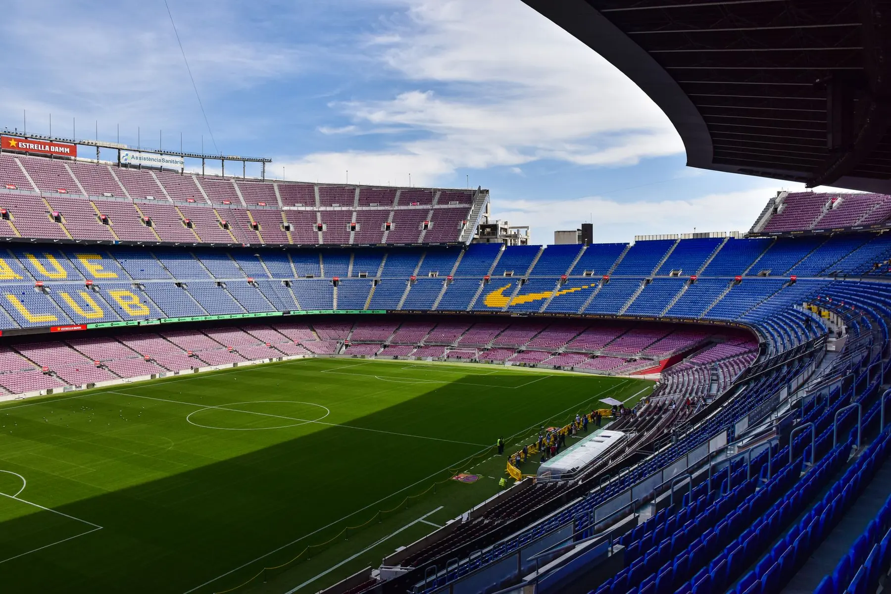 Wide angle view of Camp Nou stadium with blue and red seating and a green football pitch
