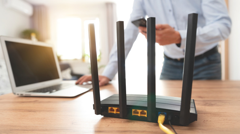 Wi-Fi router on desk with person in background configuring it.