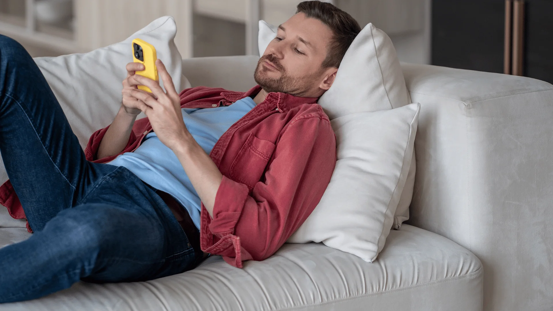 man in blue shirt on the phone saying i don't feel like trying today as he lays on the couch 